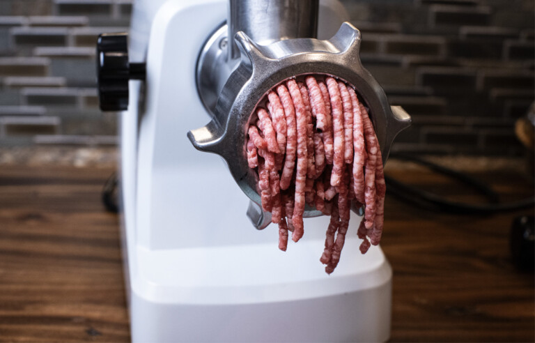 ground beef coming out of meat grinder on bench top