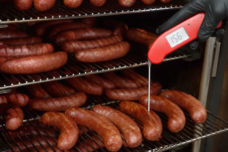 sausages in a smoker checking their temperature with probe