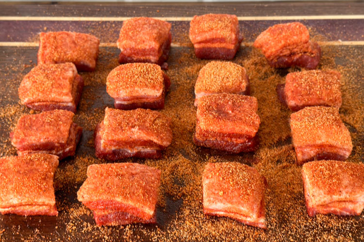 seasoned pork belly cubes on a wooden board