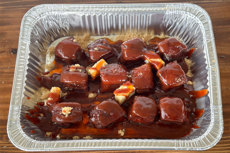 pork cubes in a foil pan with glaze ingredients