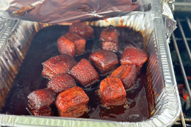 aluminum foil pan with pork belly burnt ends in sauce