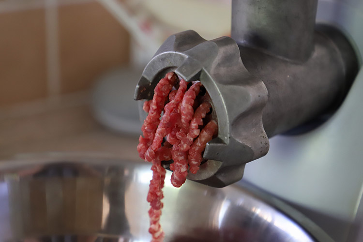 a close-up view of the meat grinder with ground beef