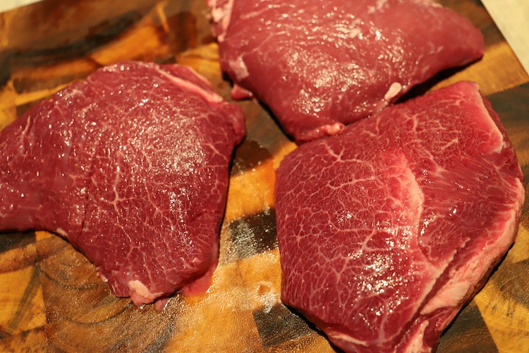 raw beef cheeks on a wooden board
