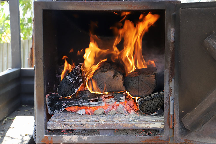 burning wood logs fueling an offset smoker