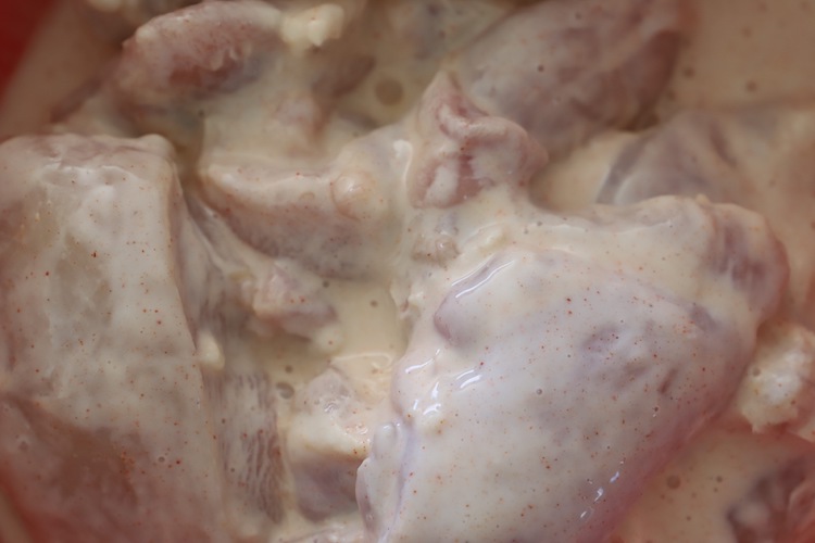 uncooked chicken thighs covered in buttermilk brine