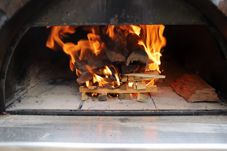 hardwood kindling and firewood burning in a pizza oven