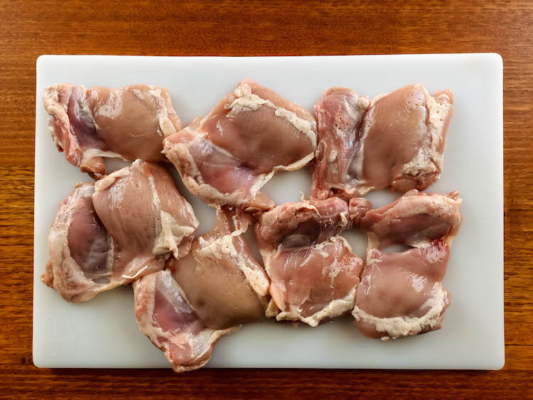 raw chicken thighs on a white board