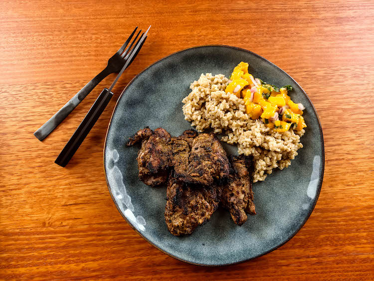 grilled jerk chicken thighs with rice and mango salsa on a plate