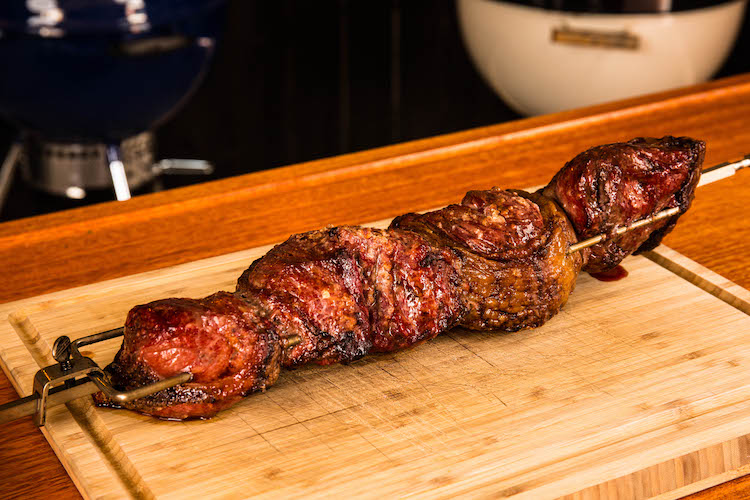 rotisserie skewer with cooked picanha on a wooden board