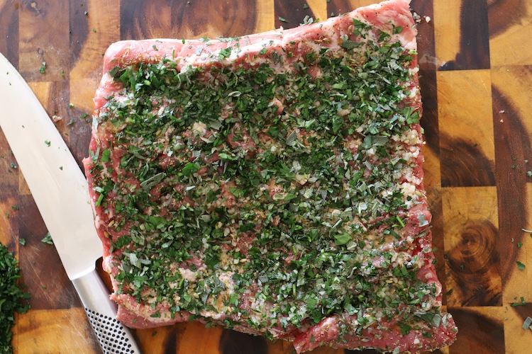 uncooked pork belly rubbed with herbs and spices