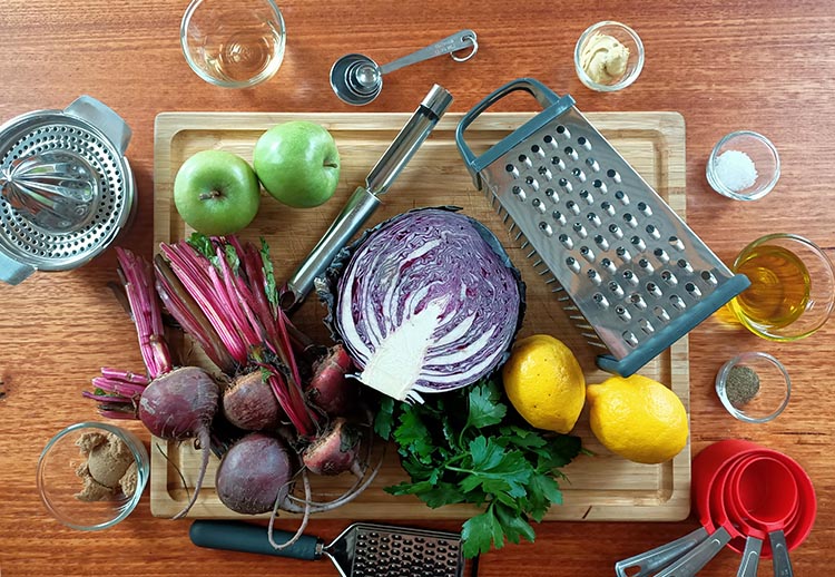 apples, beets, lemons and other slaw ingredients on a wooden board
