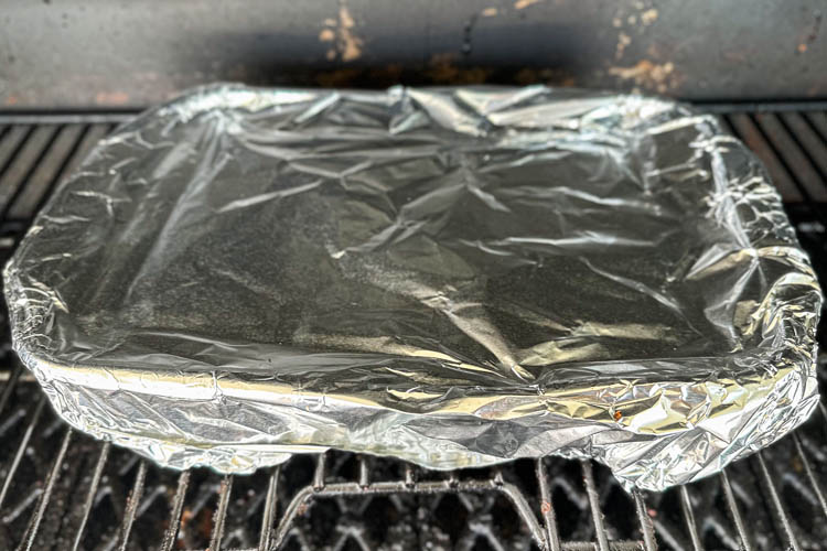 pan covered in fil in smoker
