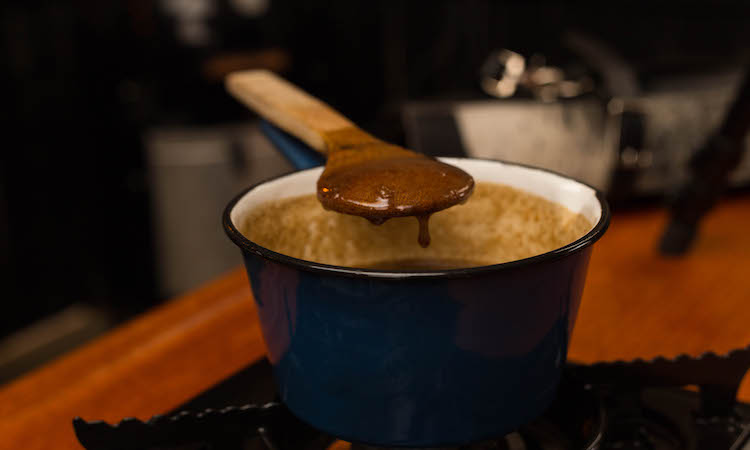 a wooden spoon covered in maple glaze on a saucepan