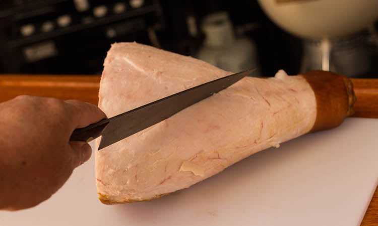 slicing the ham in the fat with a knife