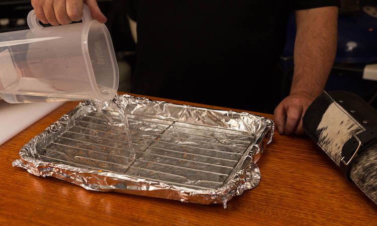 pouring water into a baking pan covered with foil