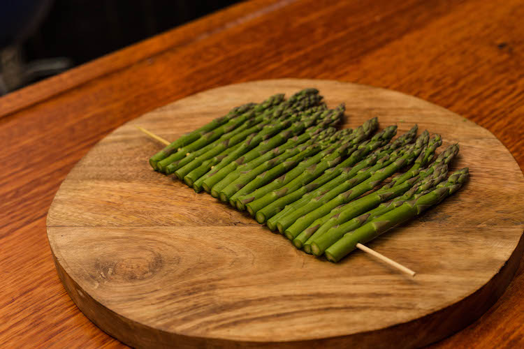 asparagus threaded on a skewer on a wooden board