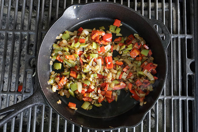 sliced bell peppers and onions cooking on a skillet