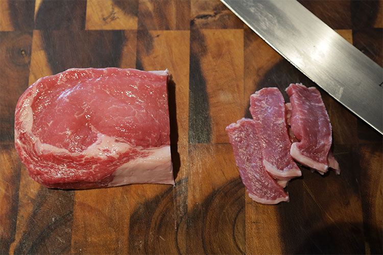 Sliced ribeye steak on a wooden board