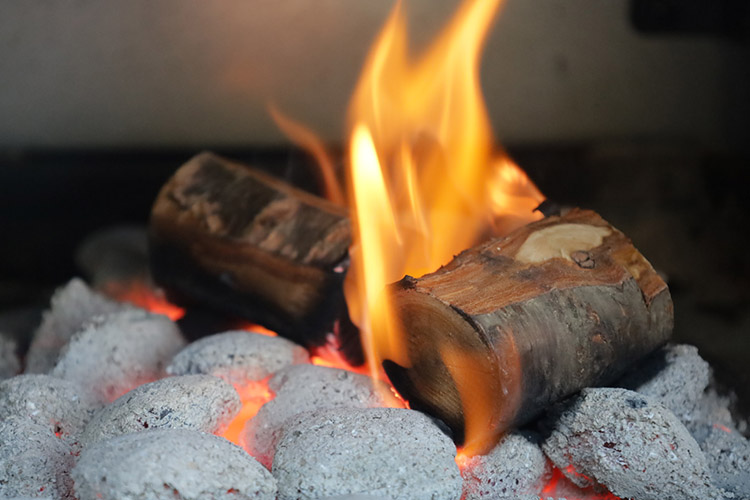 pecan wood chunks burning on top of charcoal