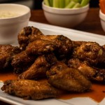Buffalo wings and blue cheese sauce on a white plate
