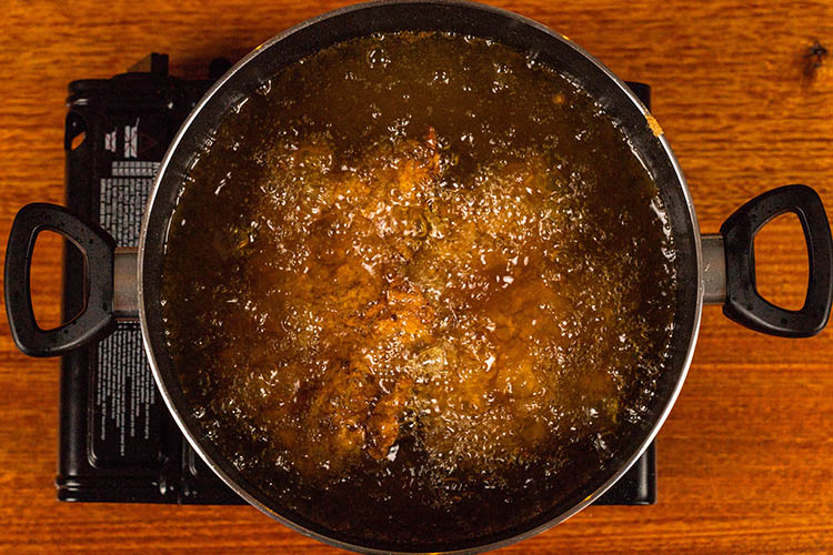 chicken thighs frying in oil in a frying pan