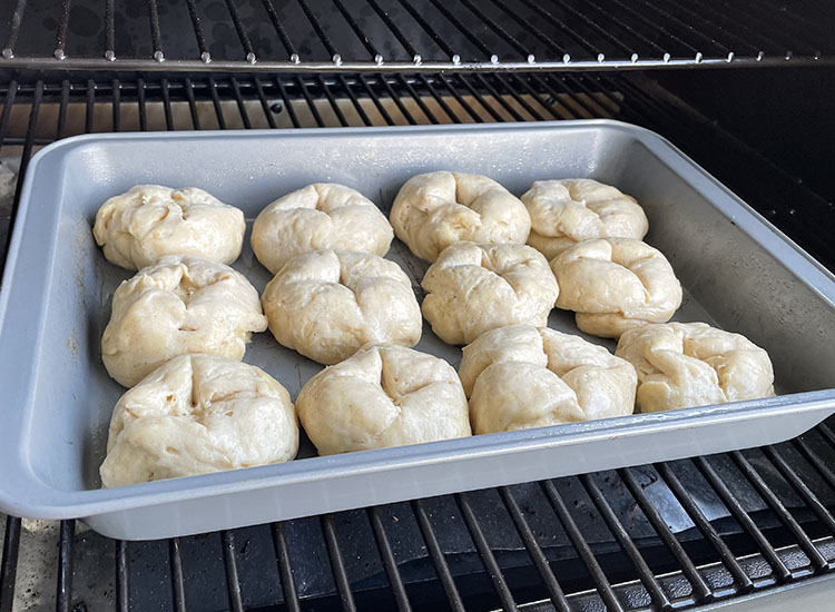 uncooked hot cross buns on a baking tray on a grill