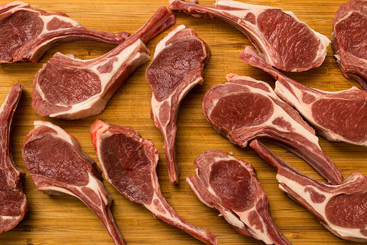 uncooked lamb cutlets on a wooden board