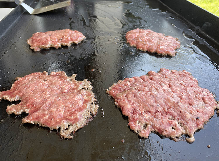 smash burger patties cooking on a griddle