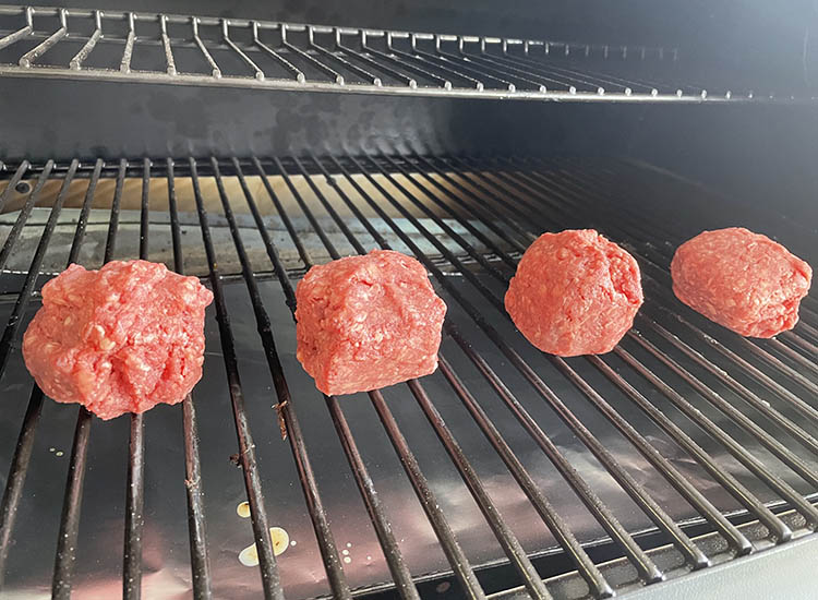 four ground beef balls in a smoker