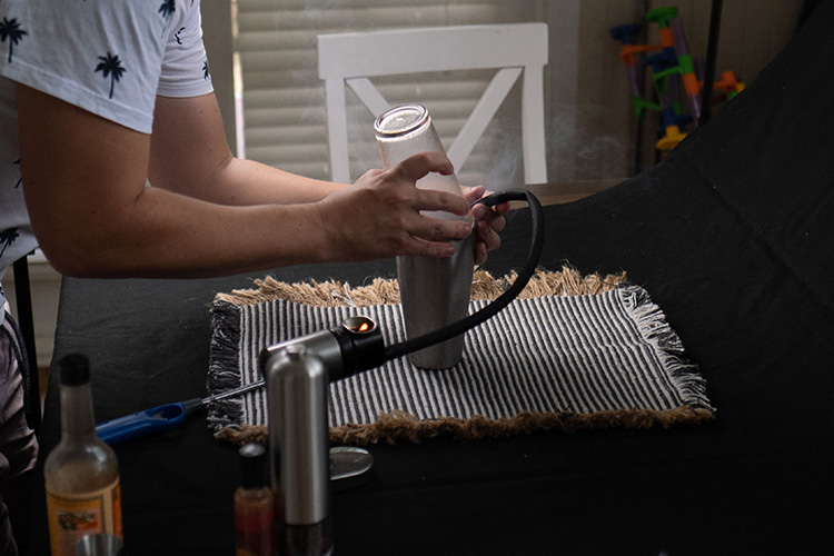 a process of adding smoke into a cocktail shaker using a smoking gun