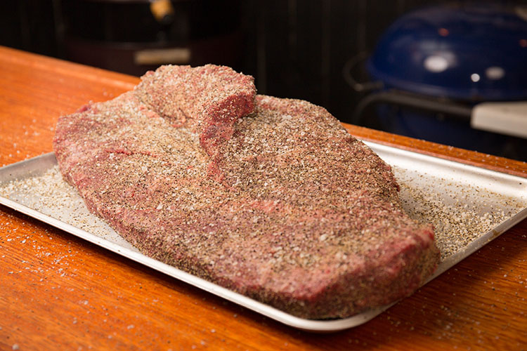 uncooked beef brisket seasoned with salt pepper garlic on a metal tray