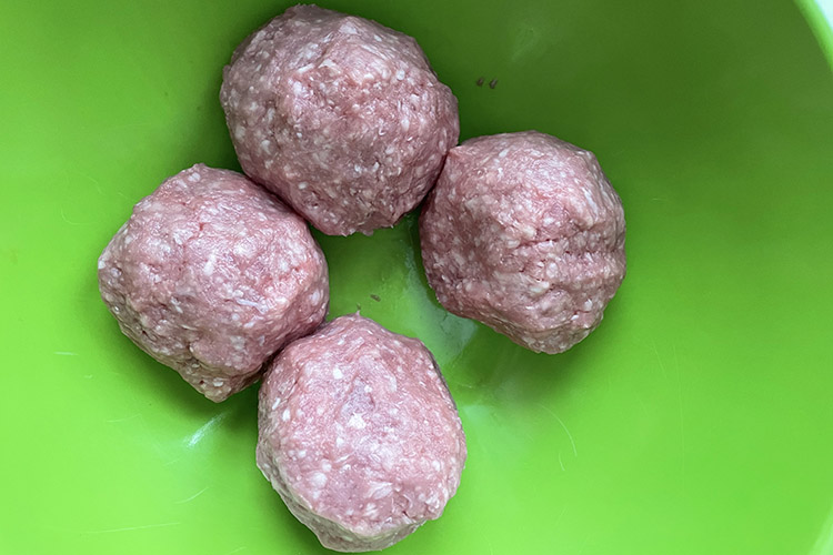 ground lamb rolled into balls in a plastic bowl
