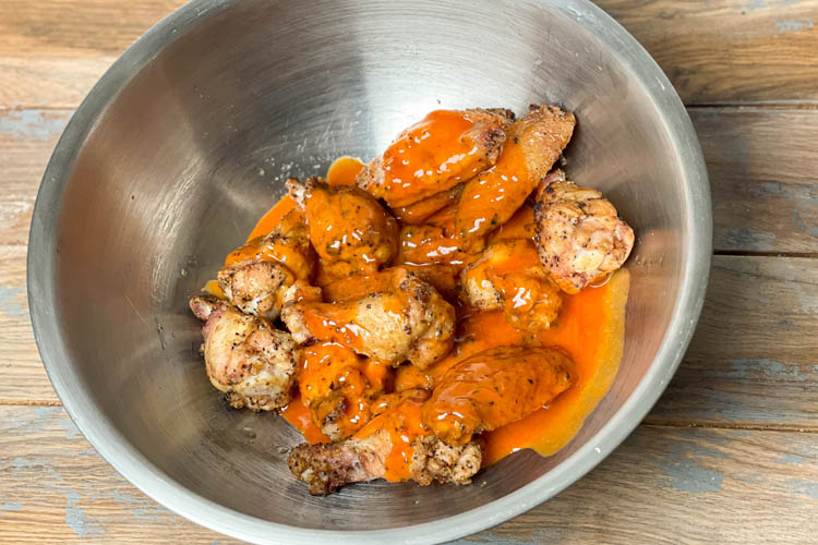 cooked wings in a bowl with buffalo sauce