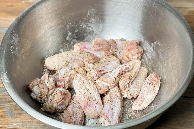 raw seasoned chicken wings in a silver bowl