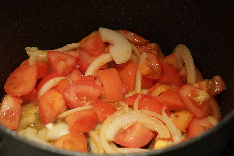 sliced tomato and onions in a pan
