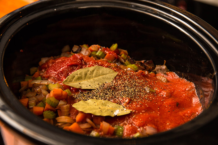 brisket, vegetables, tomato paste and bay leaves in a slow cooker