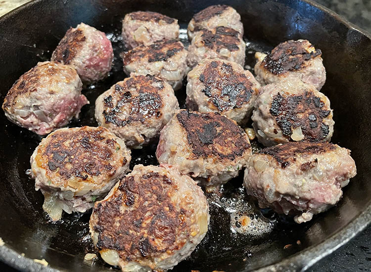 venison meatballs searing in a cast iron pan