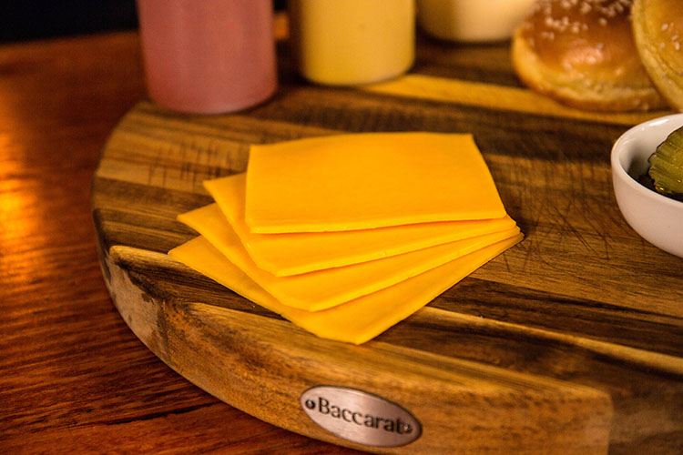 sliced cheddar cheese on a wooden board