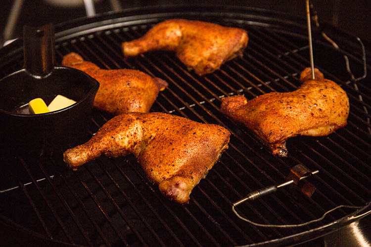 cast iron pan and chicken legs on a smoker