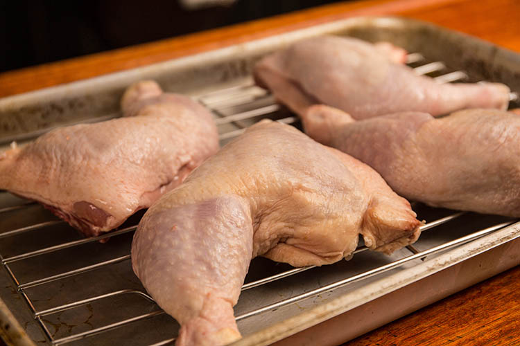 raw chicken legs on a metal baking tray