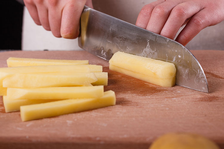 a person slicing potato into strips