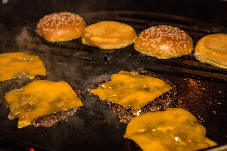 smash burger patties with cheese on a hotplate
