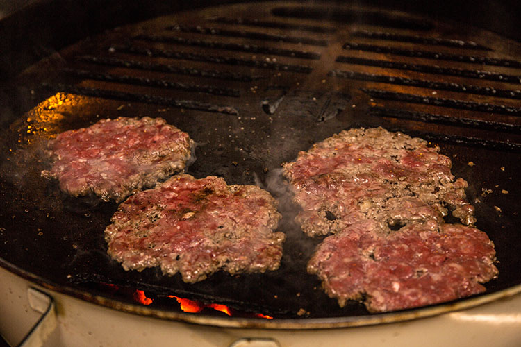 smashed burger patties on a weber kettle