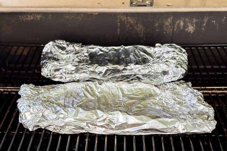 ribs wrapped in foil on the smoker