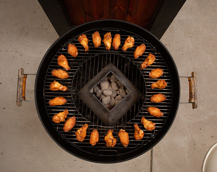 Chicken placed in a circle around the outside of the weber grill cooking