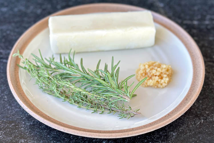 rosemary, thyme, garlic and butter on a white plate