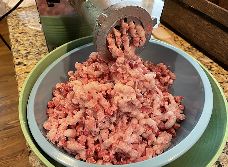 meat grinder with a large plate and a bowl full of ground meat