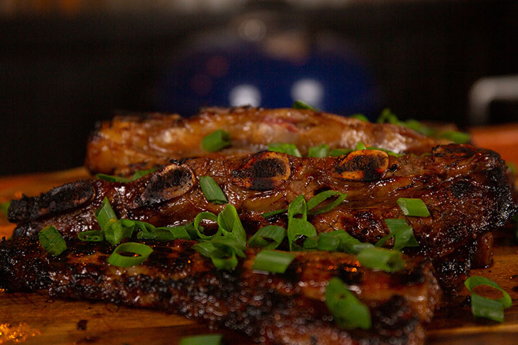 korean bbq ribs garnished with green onions on a wooden board
