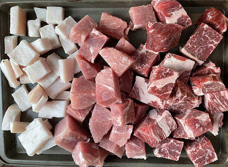 pork and beef sliced into cubes on a metal tray
