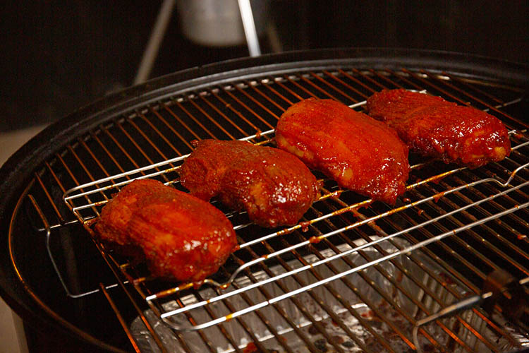 Glazed chicken breasts sitting on a wire rack in the smoker